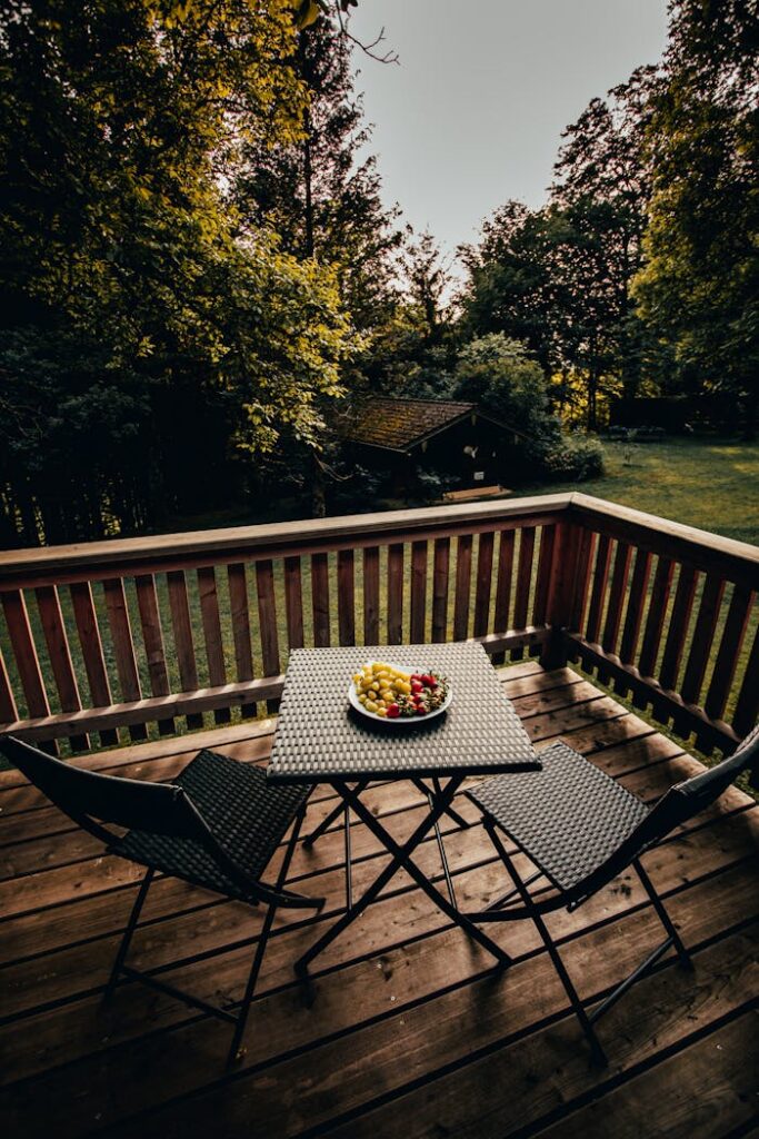 A serene patio setup with rattan furniture, surrounded by lush greenery and a calming forest view.