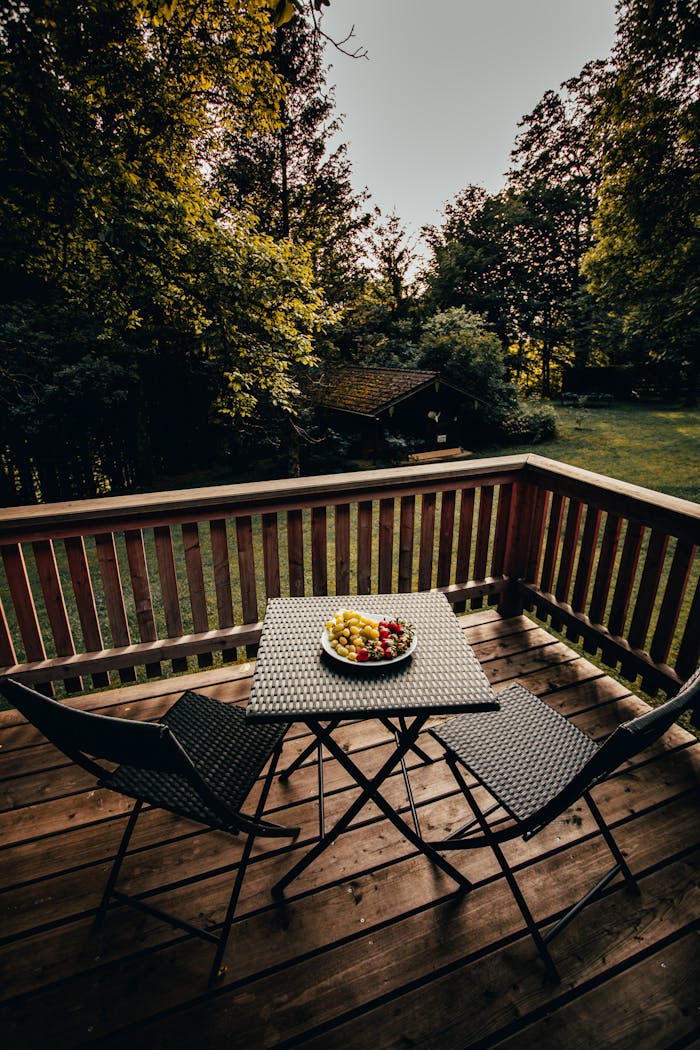 A serene patio setup with rattan furniture, surrounded by lush greenery and a calming forest view.