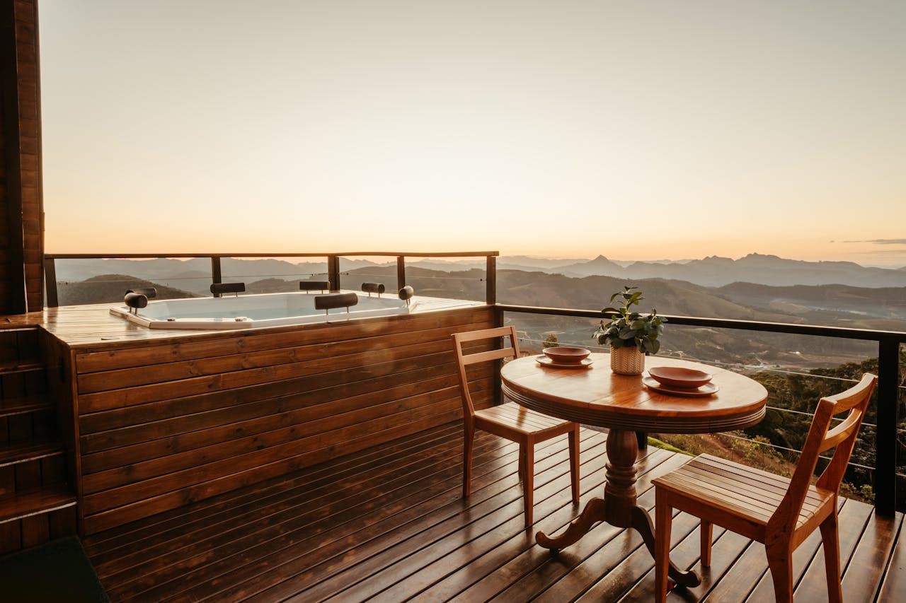 Experience serene luxury with a mountain view, jacuzzi, and wooden deck at sunset.
