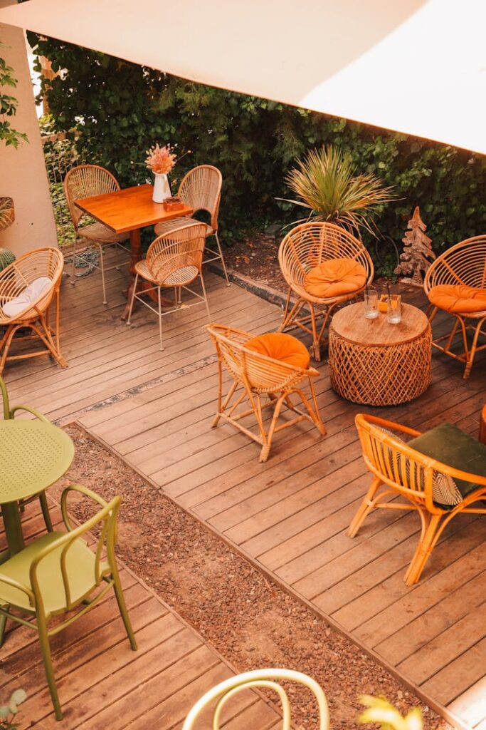Charming outdoor patio with wicker chairs and wooden tables in warm tones.
